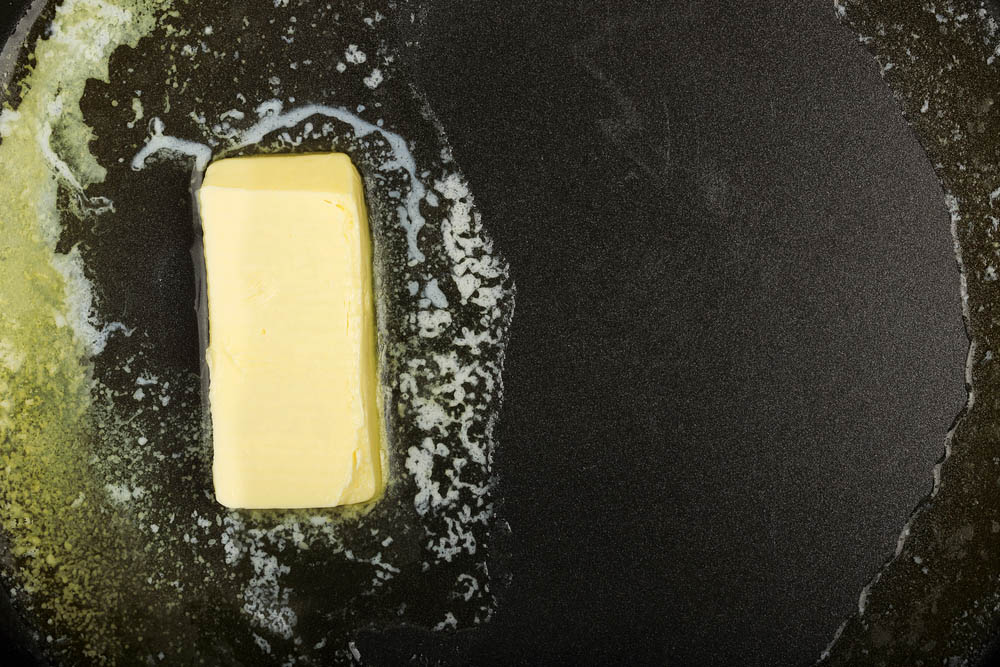 Piece of butter while melting in frying pan