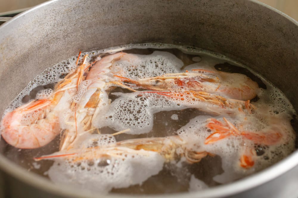 The prawns are boiled in a saucepan on a gas stove