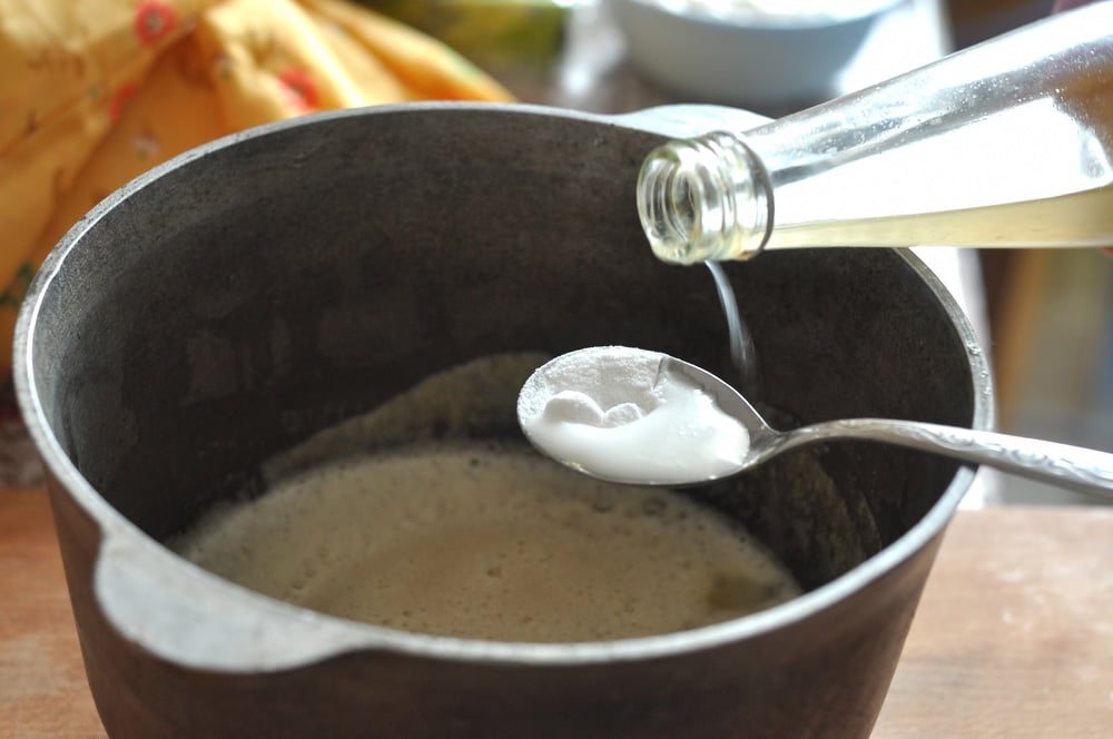 Process of quenching the baking soda with the vinegar in a spoon over a cast-iron bowl