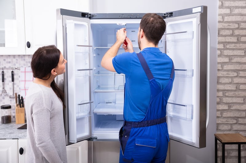 Repairman Fixing Refrigerator With Screwdriver