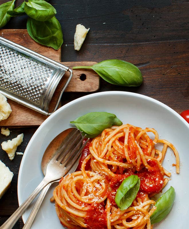 Spaghetti pasta with tomato sauce, basil and cheese on a wooden table top view