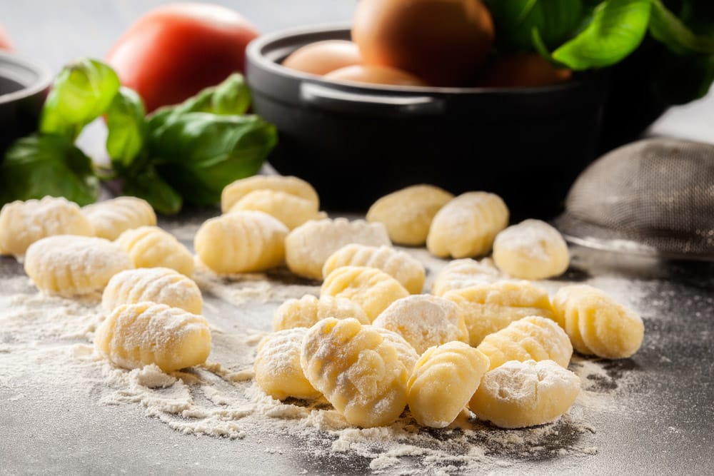 Uncooked homemade gnocchi on black cutting board