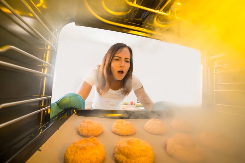 Woman Looking At Burnt Cookies In Oven