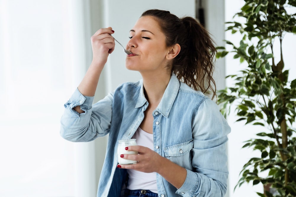 Young woman eating yogurt at home