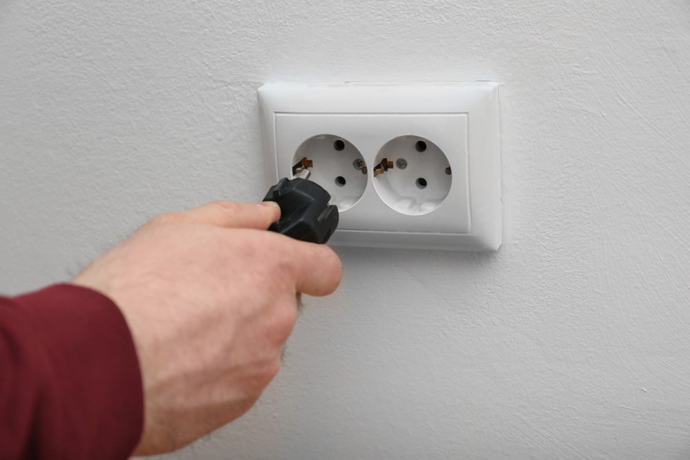 Electrician inserting plug into power socket