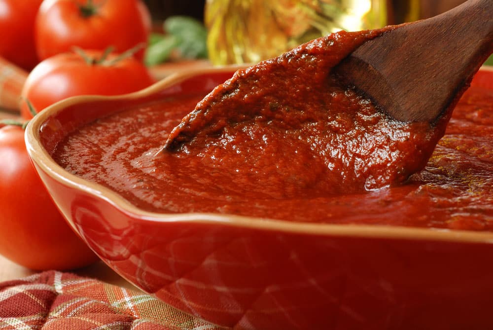 Freshly prepared pasta or pizza sauce in bowl with wooden spoon