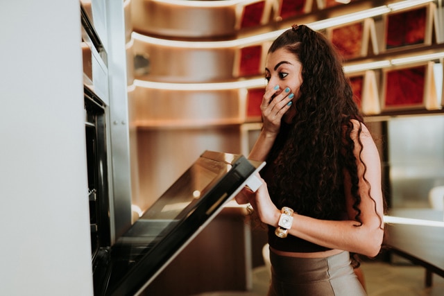 Latin woman standing by the oven and checking