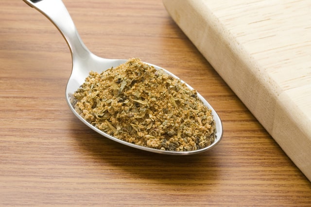 Spoonful of cajun seasoning besides a chopping board