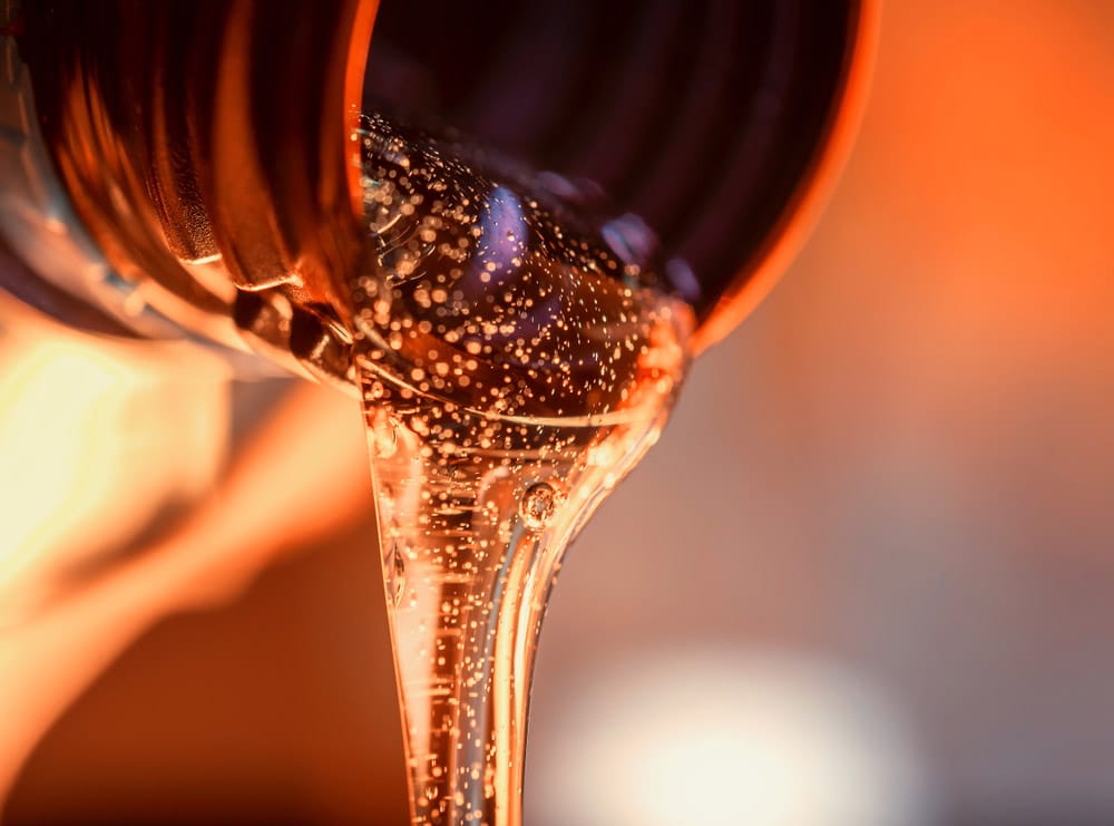Liquid stream of motorcycle motor oil flows from the neck of the bottle close-up
