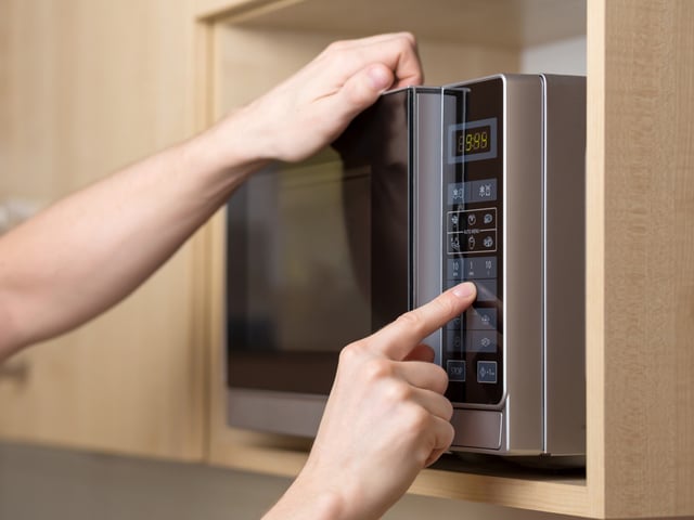 Detail of male hand while using the microwave oven