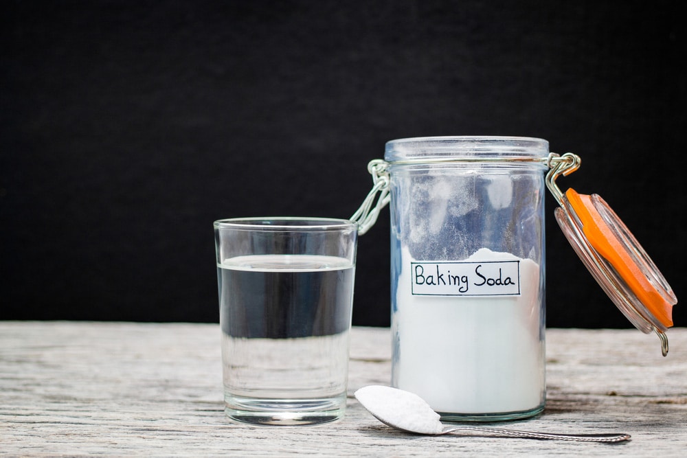 Baking soda in jar and spoonful and glass of water