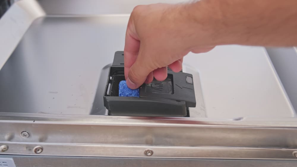 Caucasian Male Putting Detergent Capsule Pill into Dispenser on Dishwasher Door