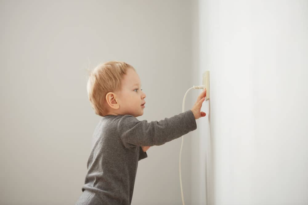 Curious little boy playing with electric plug
