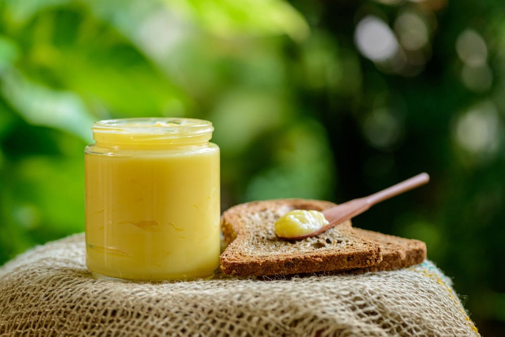 Ghee butter in glass jar with wooden spatula