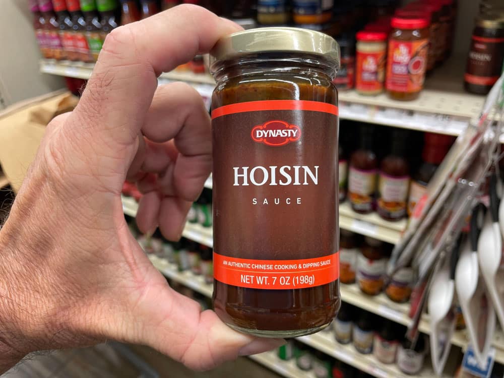 Retail store Hand holding Dynasty Hoisin Sauce in a jar