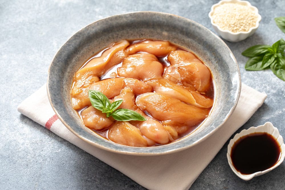 Raw diet marinated chicken meat with teriyaki sauce in a grey bowl