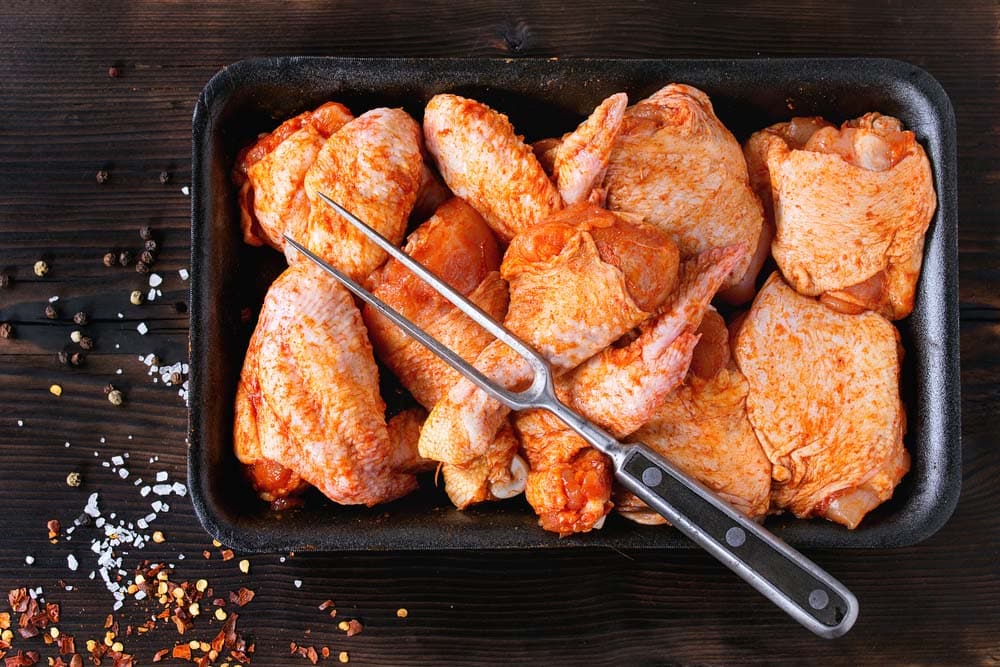 Raw Marinated chicken meat wings and legs for BBQ, served in plastic box