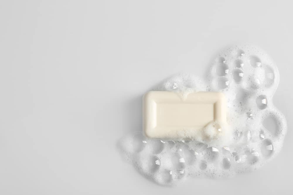 Soap bar and foam on white background