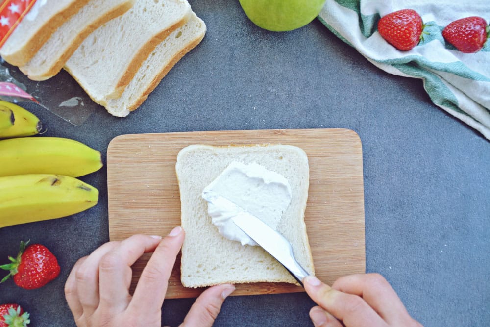 spread marshmallow cream on toast on the kitchen area surrounded by fruit