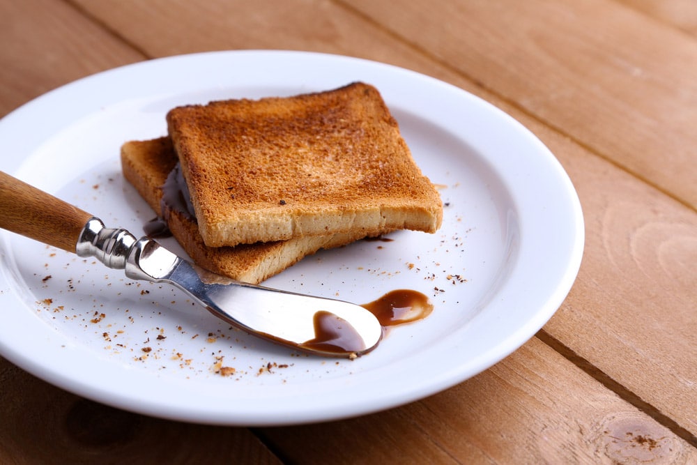 Toast bread with chocolate on plate with knife on wooden table