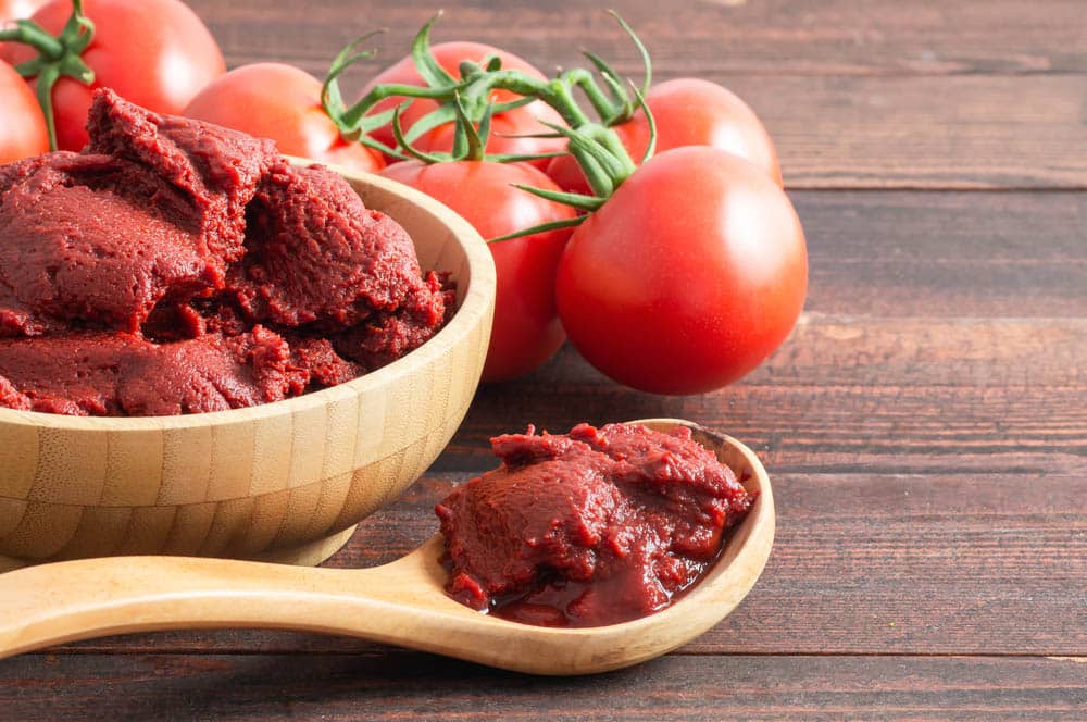 Traditional Turkish tomato paste in bowl or spoon with fresh tomatoes on wooden table