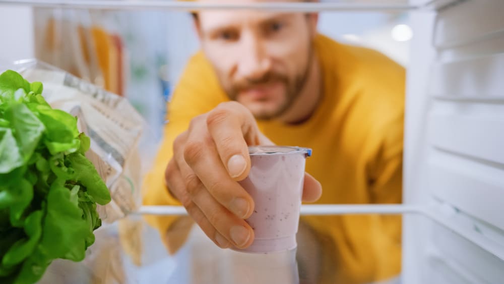 Man Opens Fridge Door, Takes out Yogurt