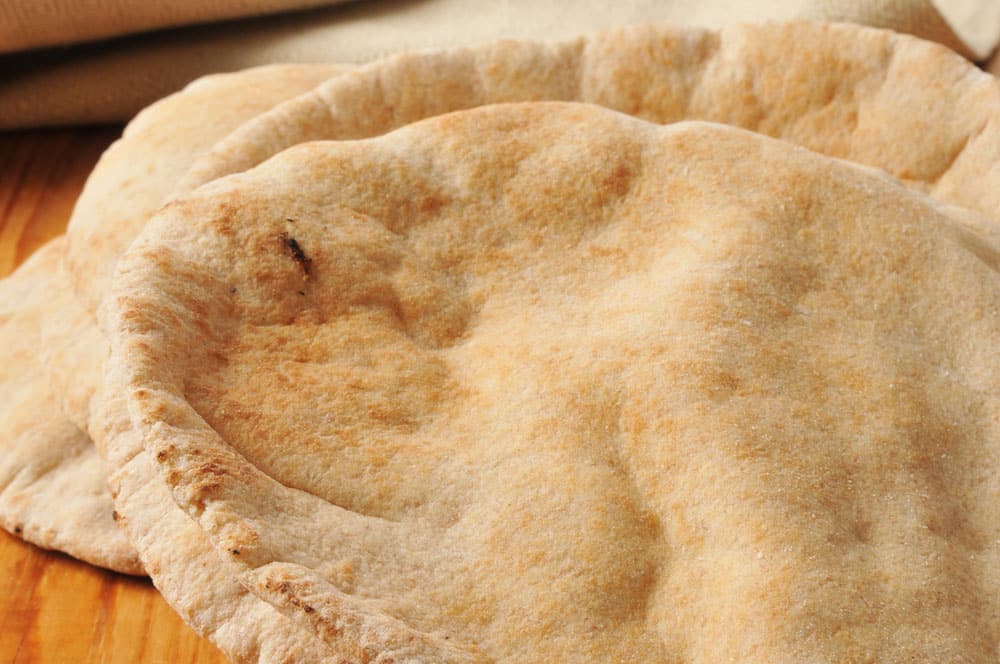 Closeup of whole wheat pita bread on a wooden cutting board