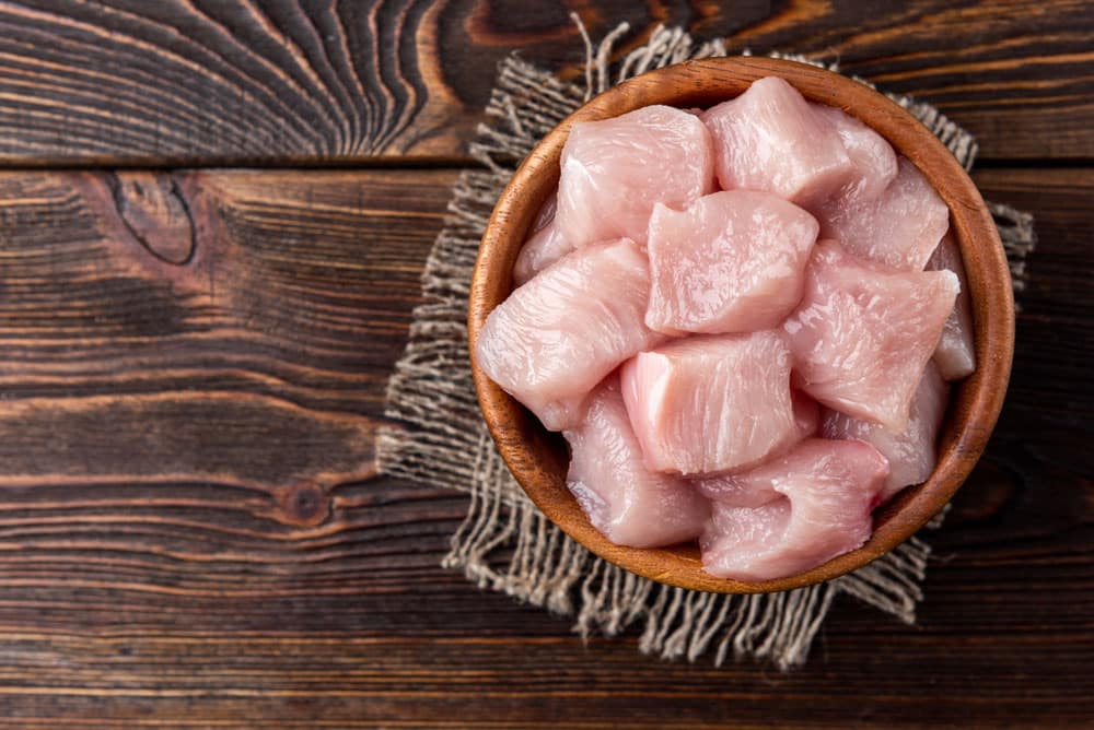 Diced raw chicken breast or fillets on dark wooden background