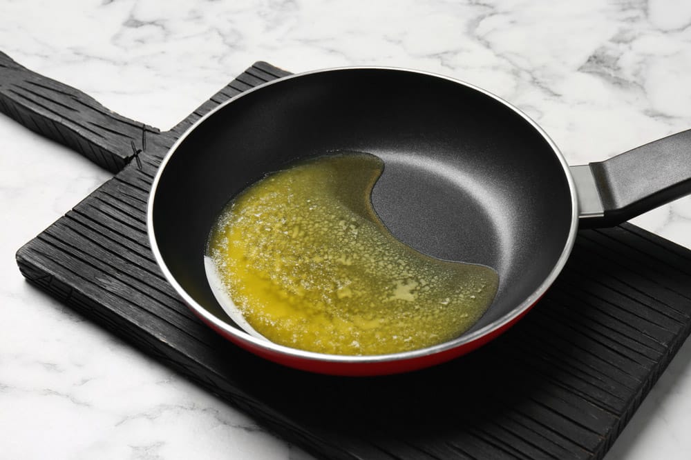 Frying pan with melting butter on marble table