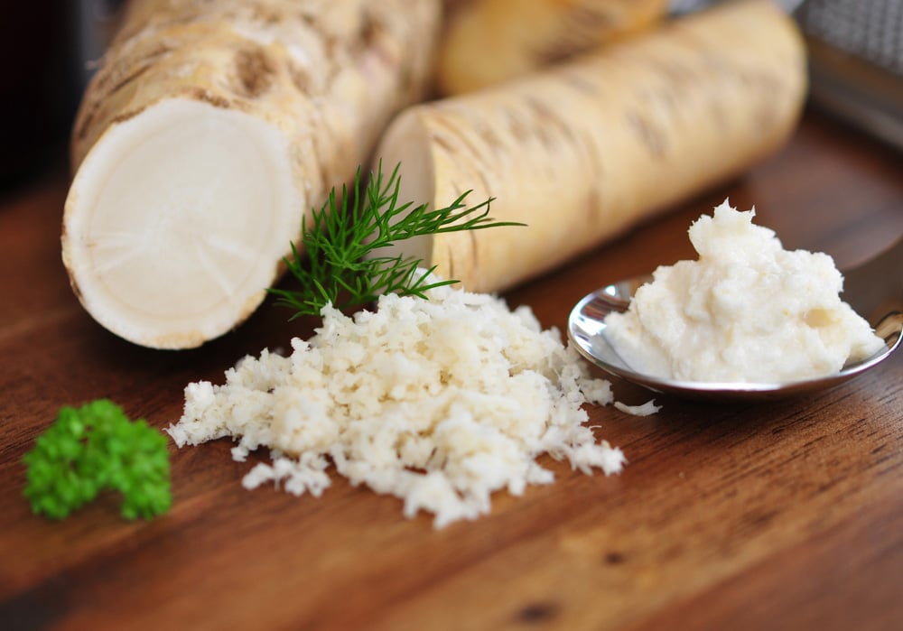 Grated horseradish with parsley on wooden table