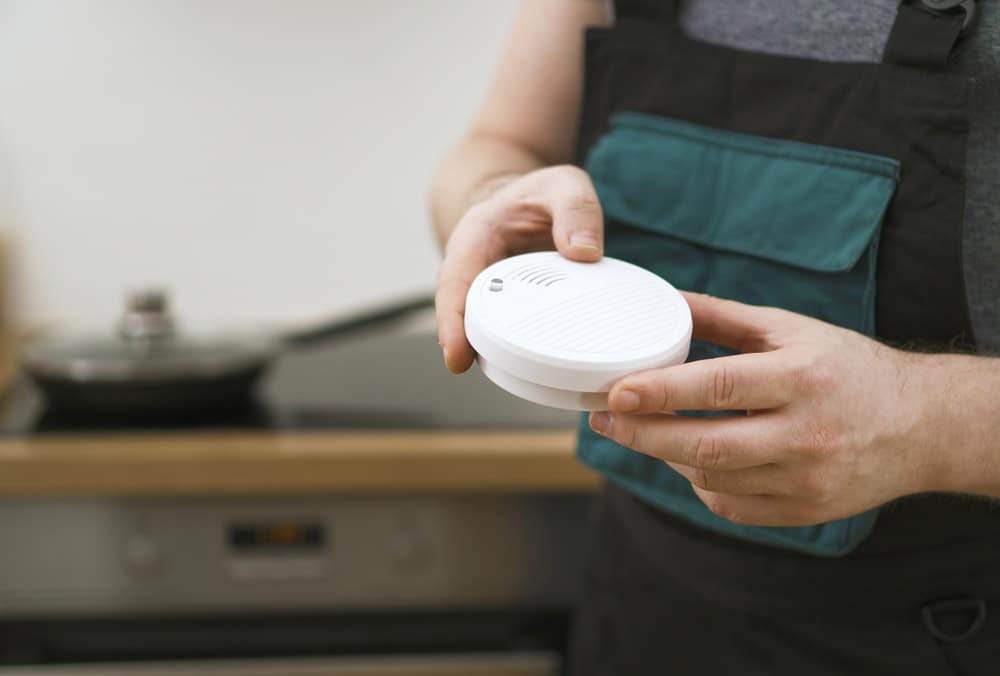 Man holding smoke detector in the kitchen