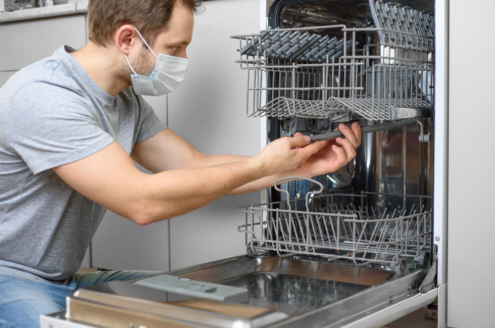 Man repairing a dishwasher with tools