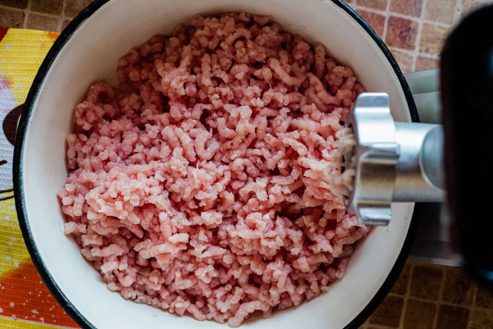 A plate of ground turkey meat and a mincer