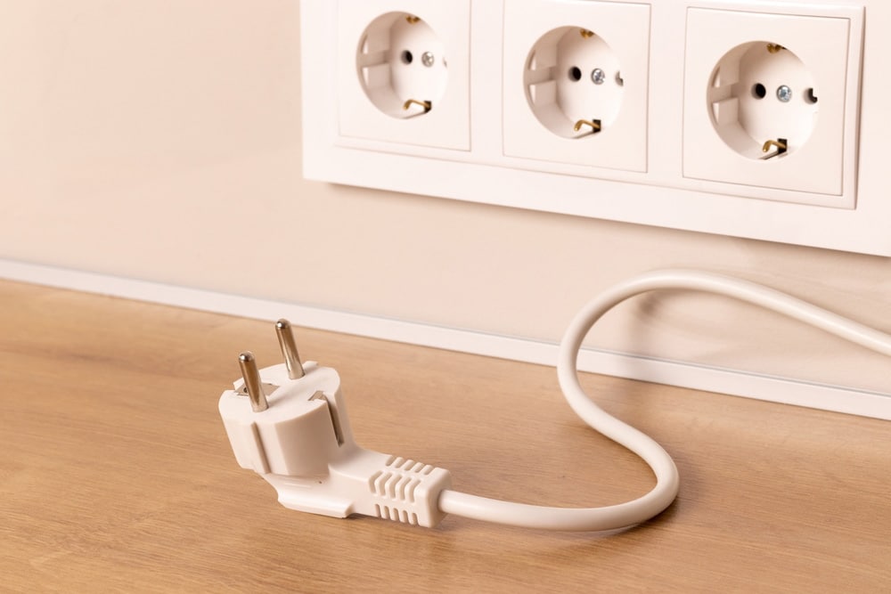 Power cord cable unplugged with group of white European electrical outlets