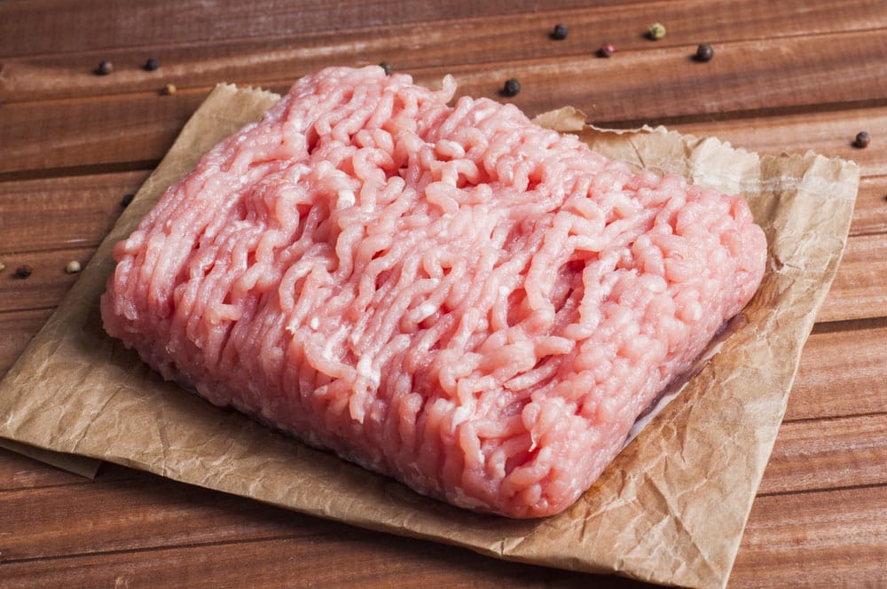Raw ground turkey meat with spices over wooden background