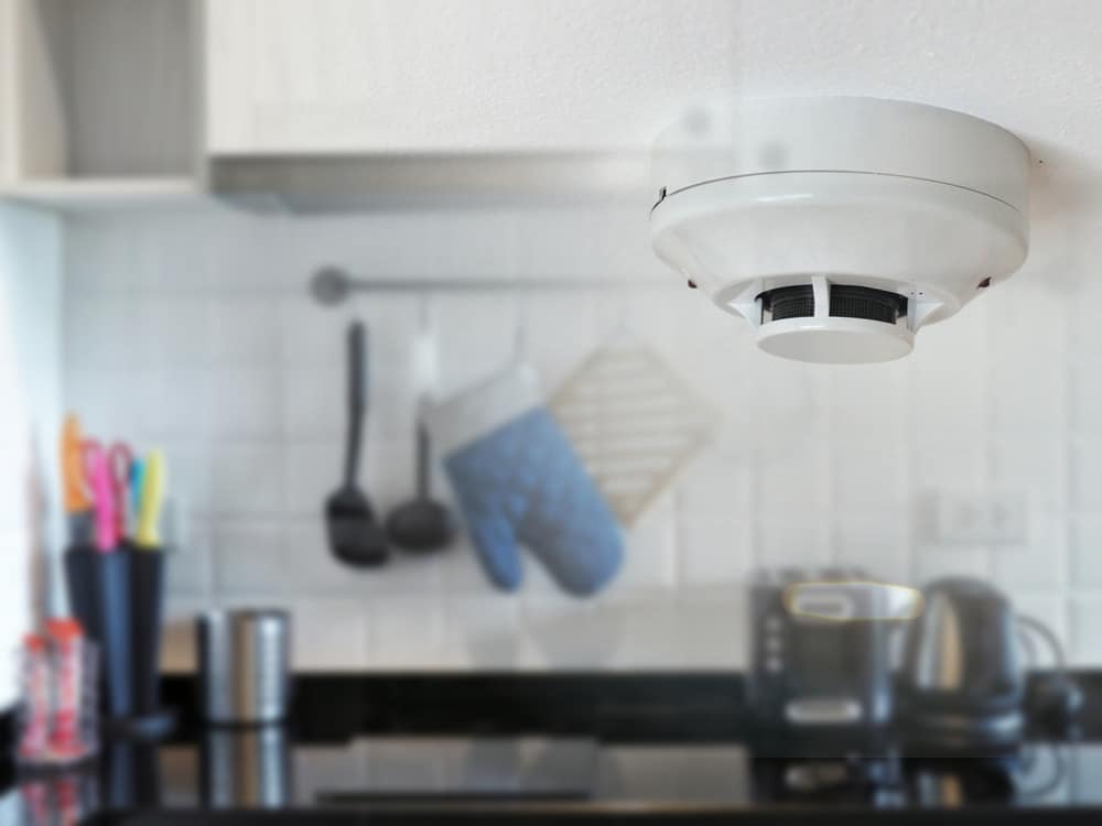 Smoke detector on the ceiling with kitchen background