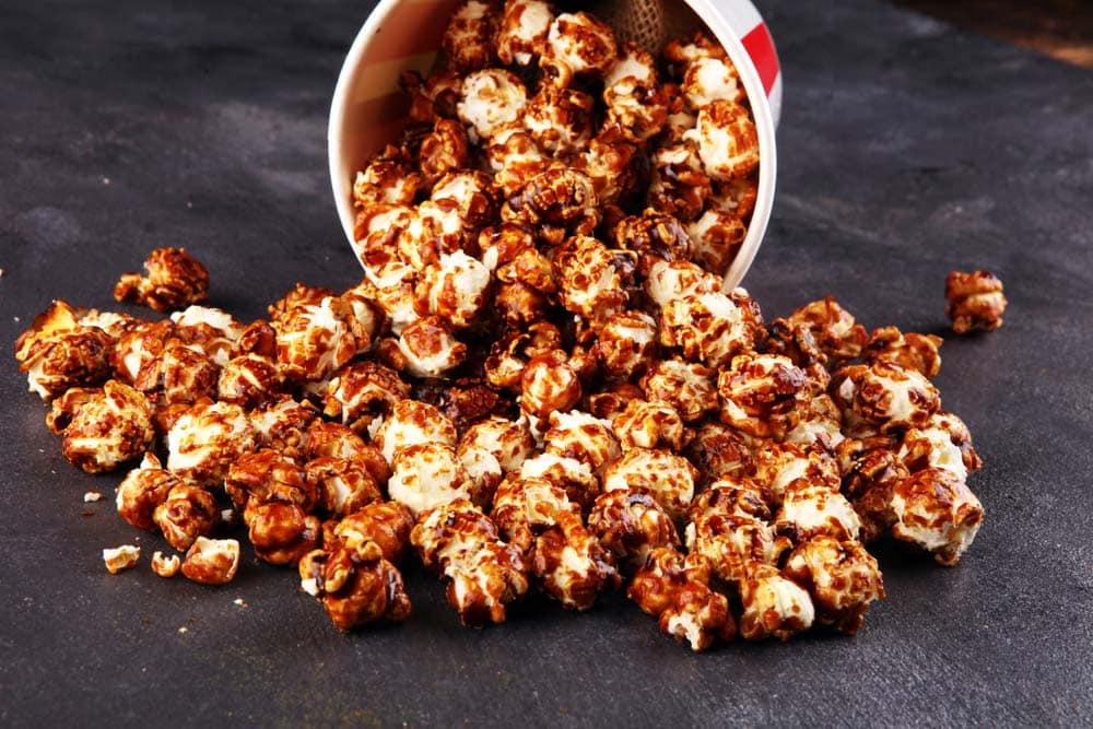 Tasty popcorn with caramel in cups on table