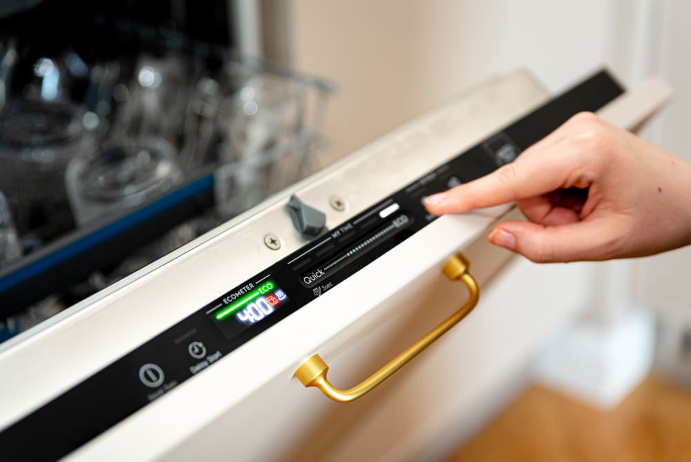 Woman choosing eco mode program on the digital control panel of the dishwasher