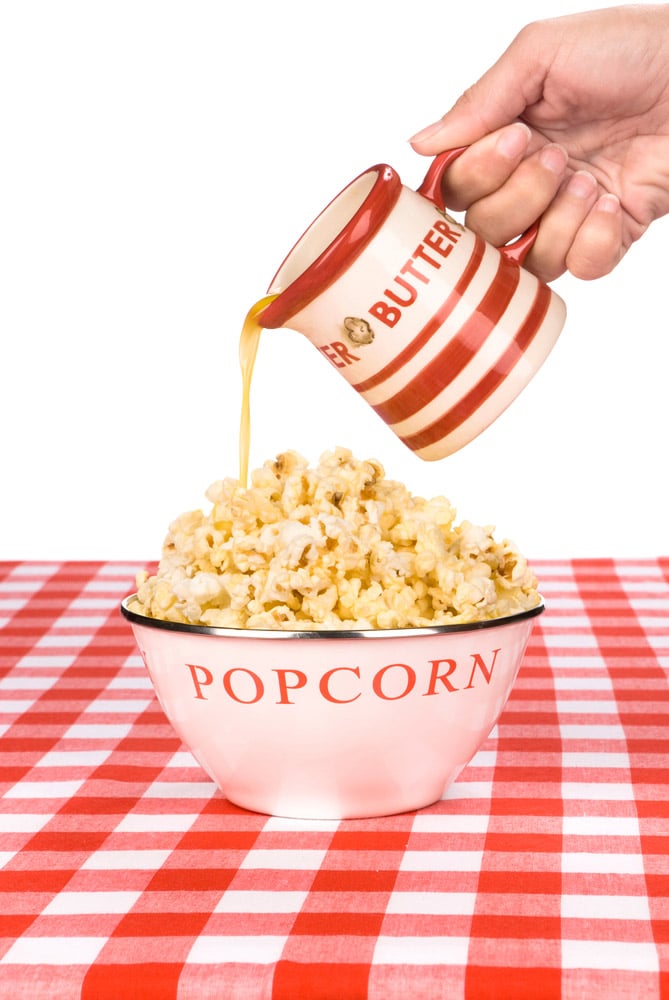 A woman pours hot butter over her bowl of popcorn
