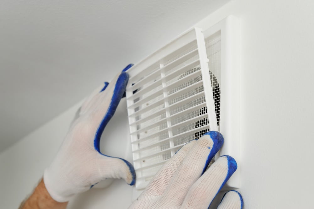 Worker installs ventilation grille on the wall