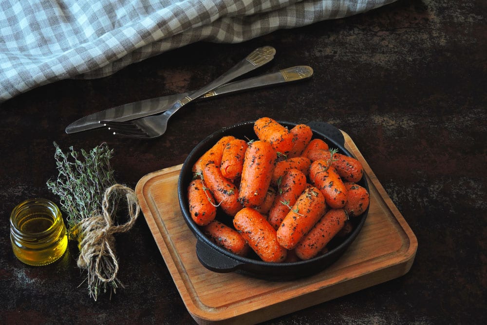 Baby carrots baked with herbs in a cast iron skillet