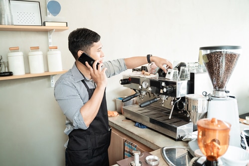 Barista checking of coffee machine when using smartphone