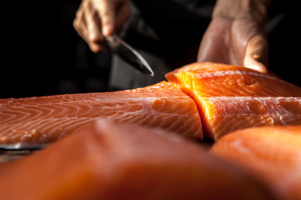 The big salmon is in the hands of the experienced Japanese chef