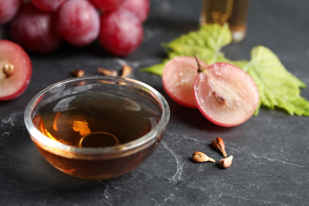 Bowl of natural grape seed oil on dark table