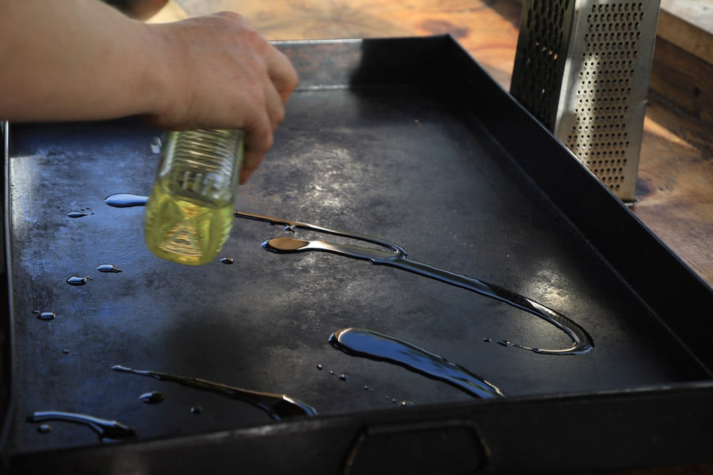 Chef pouring oil on griddle