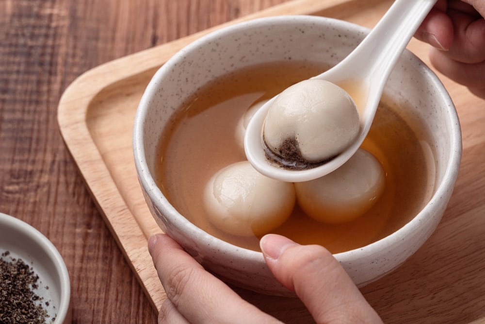 Close up of sesame big tangyuan with sweet syrup soup in a bowl on wooden table