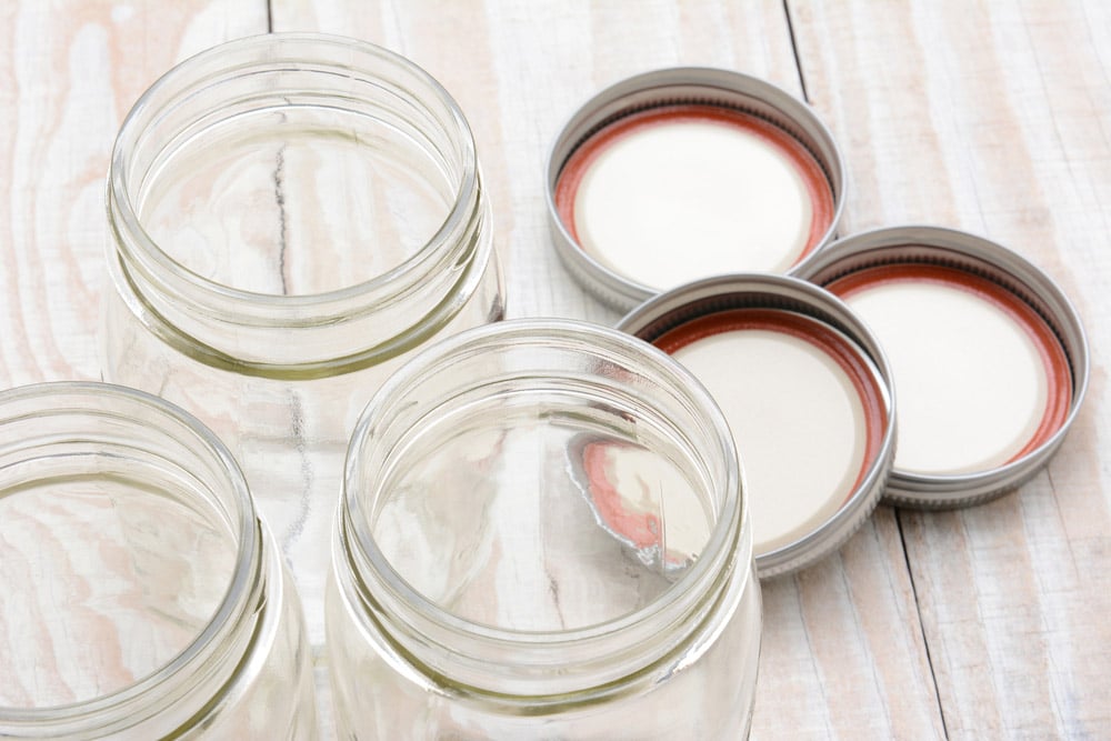 Closeup of three glass canning jars on a rustic wood kitchen table