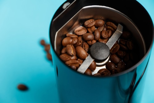 Electric coffee grinder with roasted coffee beans on the kitchen
