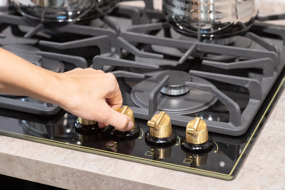Female hand turn on gas stove