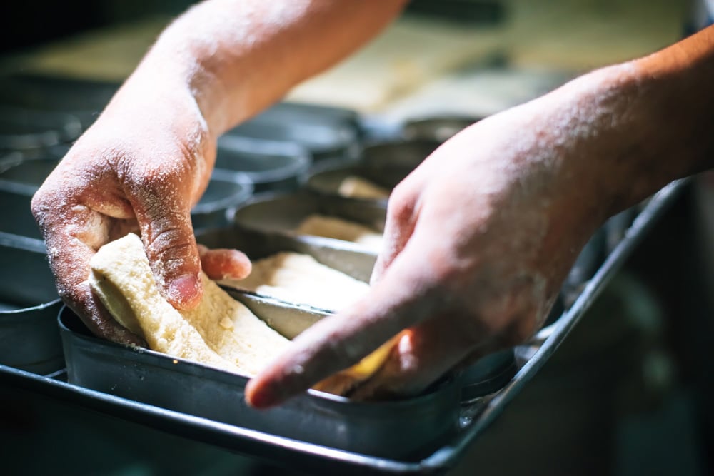 Flour-filled hands filling loaf pans